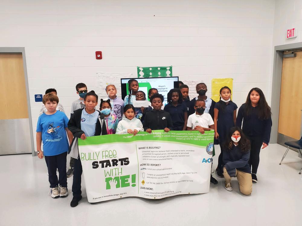 Elementary school children pose with a banner after seeing an October Bullying Prevention Month presentation 
