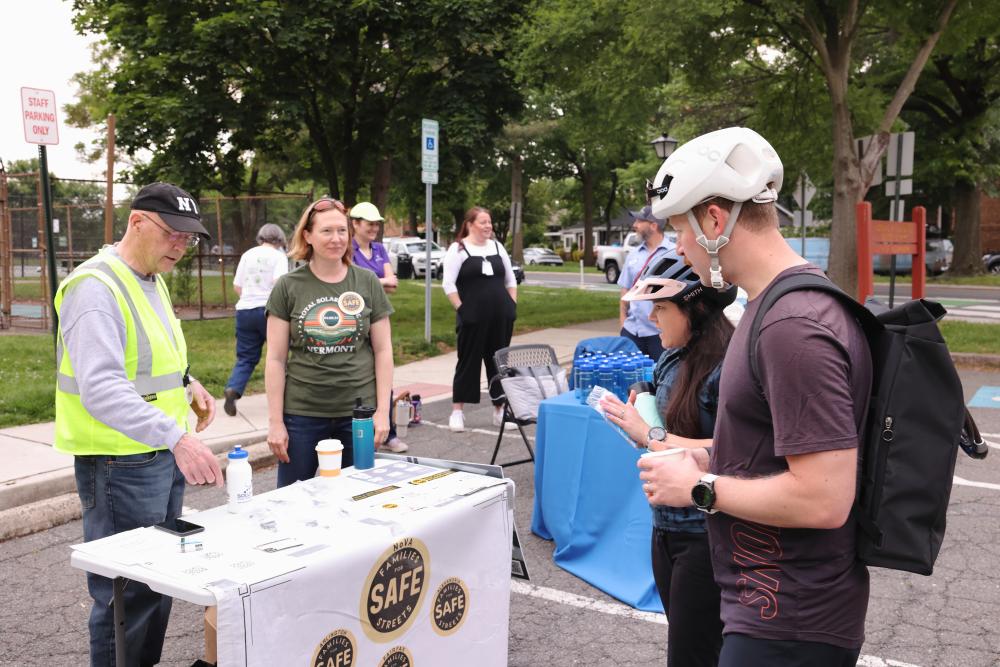 Two cyclists learn safe cycling information at a Bike to Work Day table.
