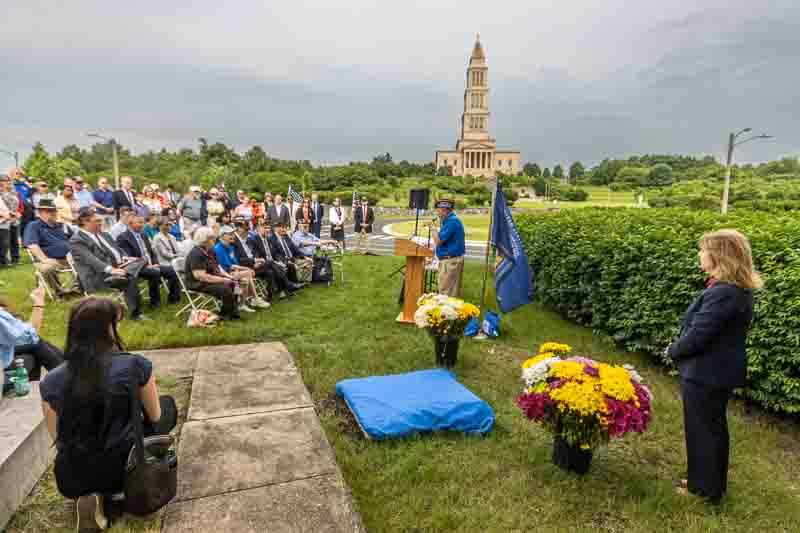 Overview of ceremony with covered plaque and Masonic Memorial in distance