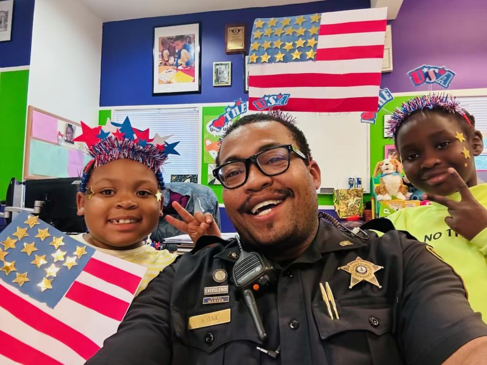 deputy with two children wearing Independence Day decorations and holding handmade U.S. flag