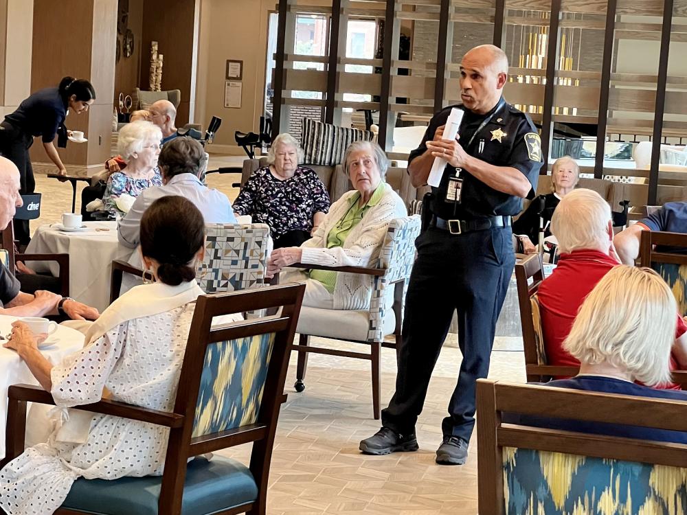 Deputy standing and speaking to several seniors seated a small tables