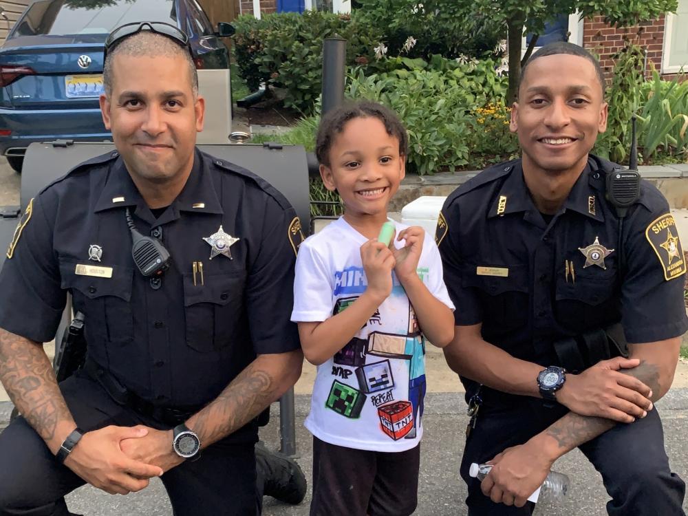 Deputies with small child, all smiling, at National Night Out