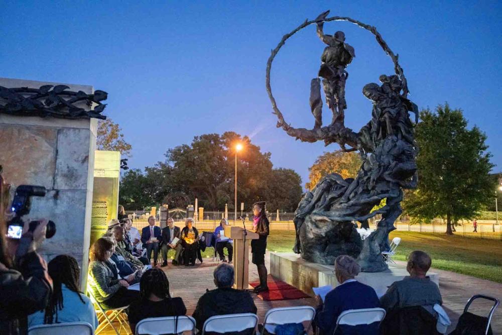 People seated and statue at dusk