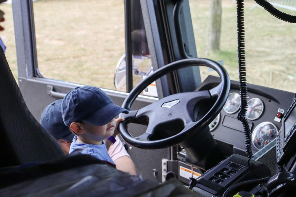 Little child holding the fire truck's steering wheel