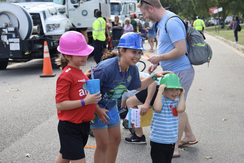Parent and two kids wearing T&ES hard hats