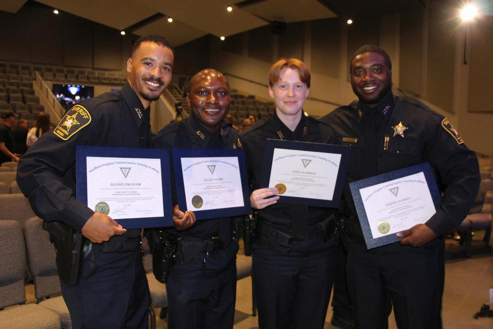 Four deputies wearing blue uniforms, holding graduation certicates and smiling