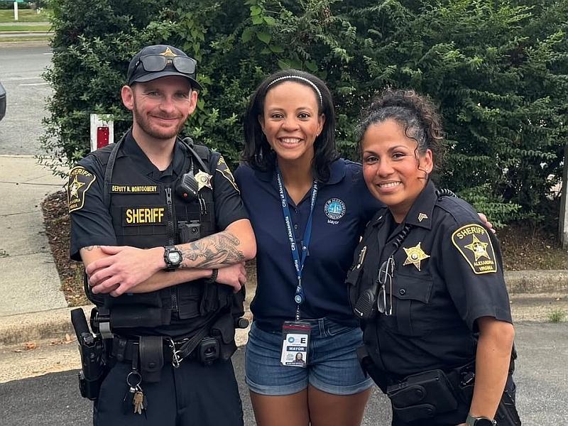 Two deputies in blue uniforms standing next to Mayor who is in the center, all smiling