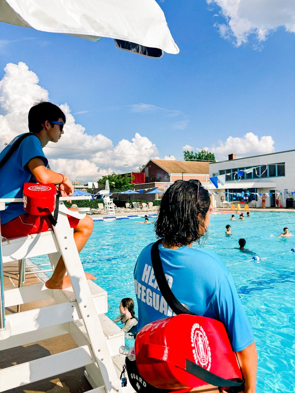 Image of two lifeguards watching an outdoor pool full of teens