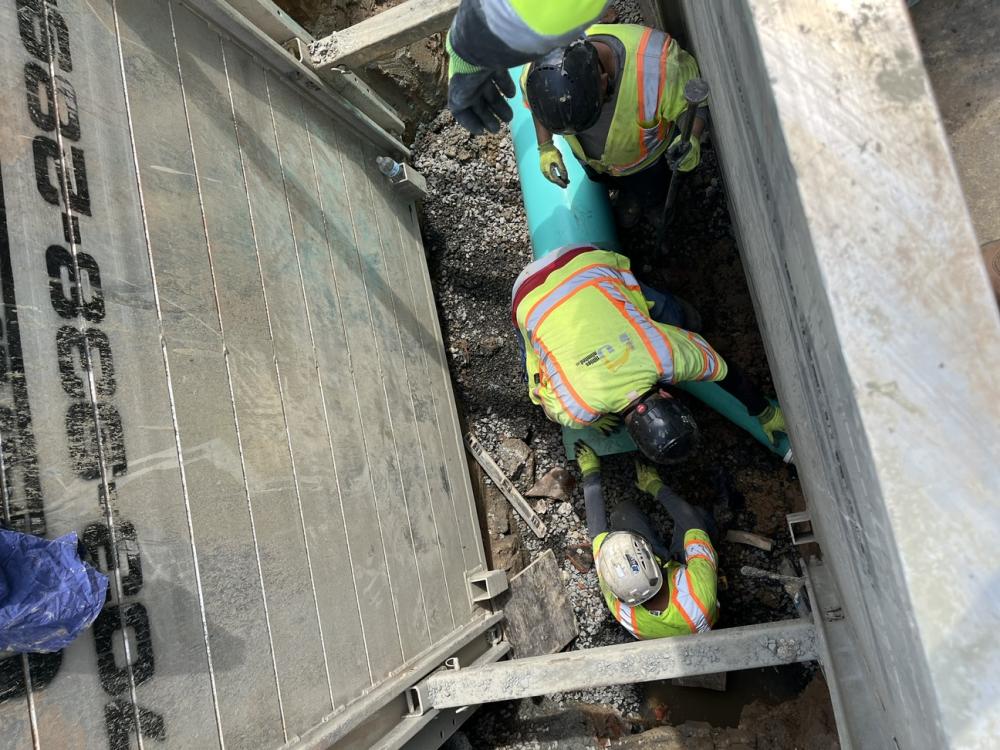 Contractors install the new turquoise SDR pipe in a supported trench