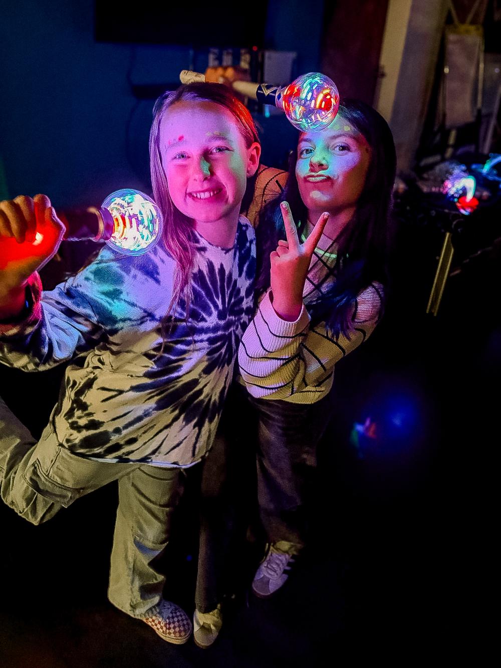 Two teen girls posing for the camera with light up microphones
