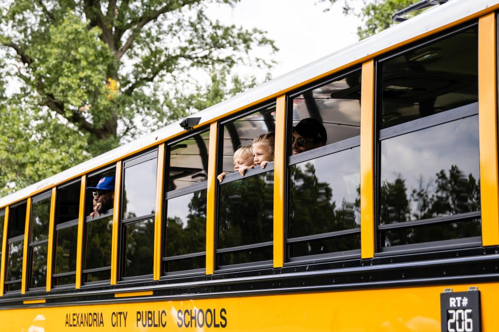 Attendees smile out the windows of a school bus