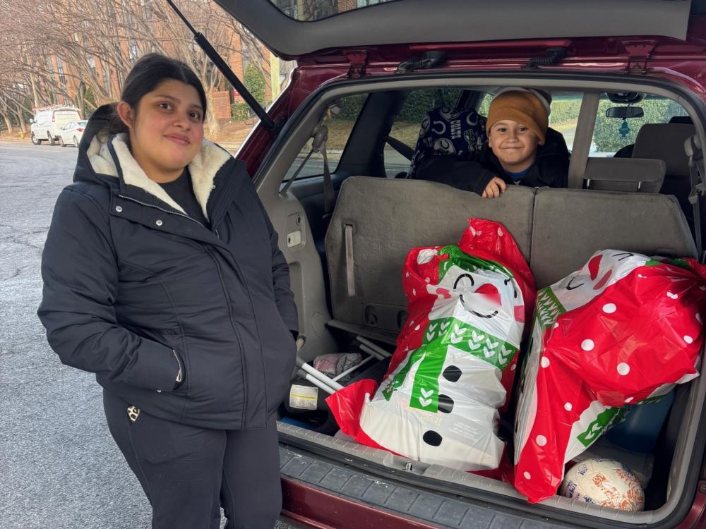 Woman and child at a car with large holiday gift bags inside