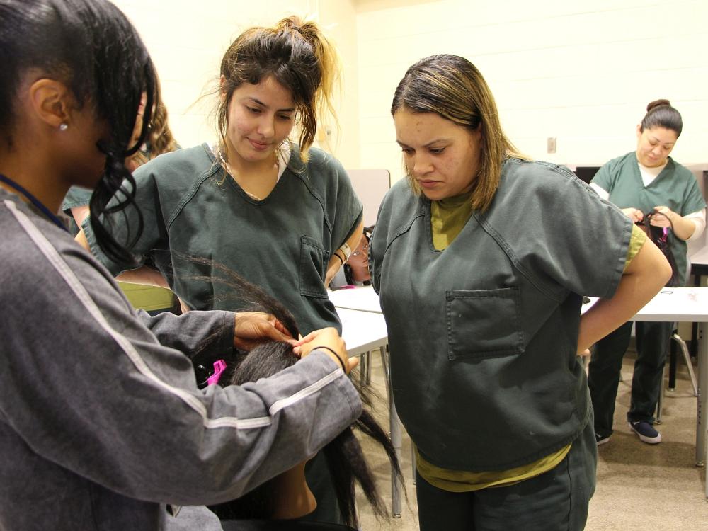 Instructor demonstrating braiding techinique to students who are inmates