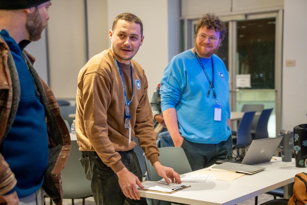 Photo of three men talking and handling paperwork