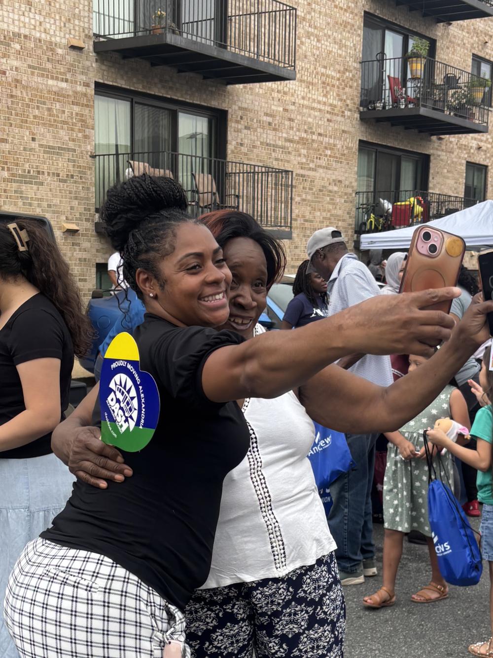 Two women smiling at the phone camera while holding the phone for a selfie