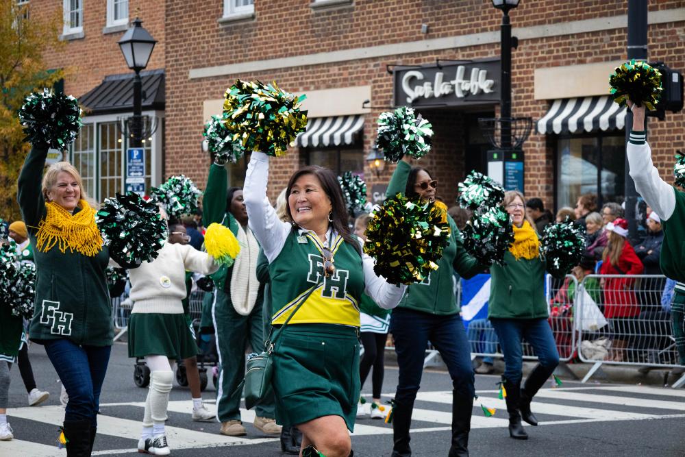 cheerleaders with pom poms waving to the crowd