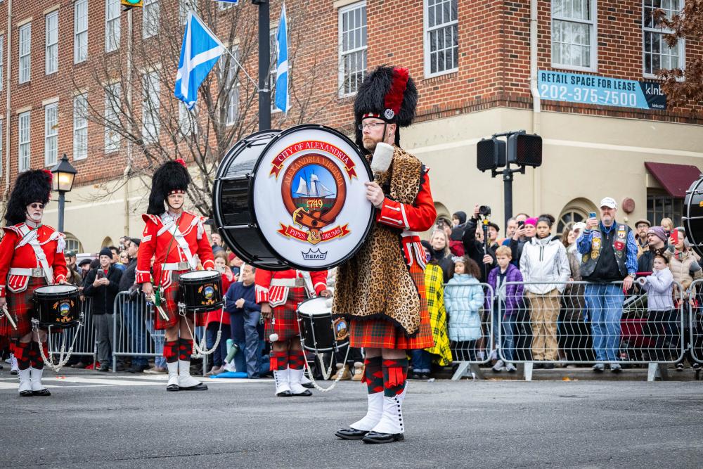 one man with large drum and two men in background playing smaller drums
