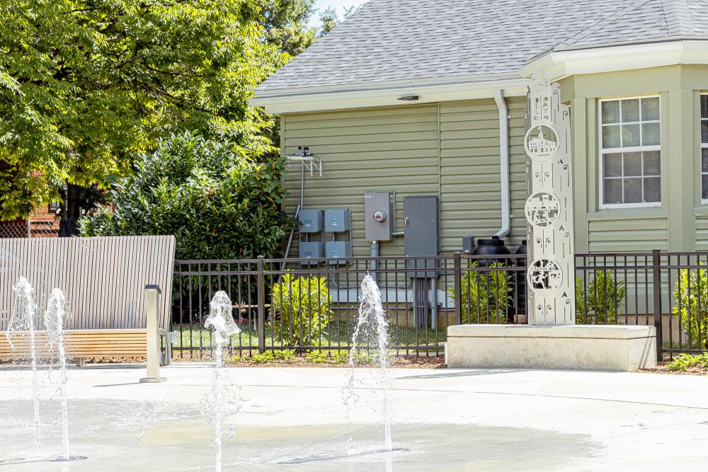 Colasanto fountain on with one part of the public art displayed on the right and wooden seating on the left