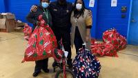 deputy and two civilians with child's bicycle and large holiday gift bags