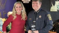 business person and sheriff holding a small trophy