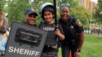 two deputies and a smiling boy holding and wearing tactical equipment