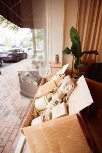 A window display of neutral-toned bath bombs, soaps, scrubs, and towels in gift boxes. The nearest one to the camera has a card that says "It's Your Birthday!"