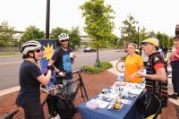 Cyclists talking by display table.
