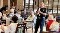 Deputy standing and speaking to several seniors seated a small tables