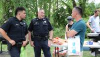 Two deputies talking with man with people grilling in the background at a National Night Out event in the Brookville-Seminary Valley neighborhood