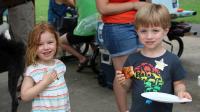 Two small children, each wearing a junior deputy sticker, smiling at a National Night Out event.