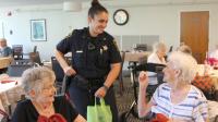 Deputy standing and talking with two residents of The View who are seated at dining table.