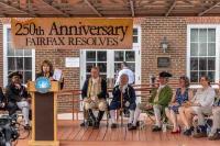 Gretchen Bulova at podium, dignitaries on stage, some in Colonial attire