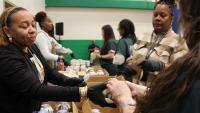 three professional staff members serving small cakes in containers to three inmates