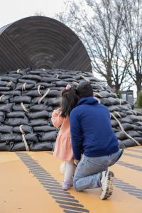 A family observes the Break Water sculpture
