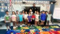 deputy in blue uninform standing with several elementary students in a classroom