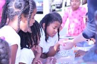 A close up of a young girl examining art supplies. 