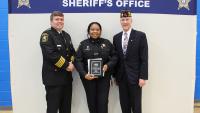 Sheriff in formal uniform, deputy in blue uniform holding award plaque and official in civilan attire wearing American Legion hat 