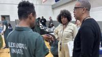 Inmate in a green jumpsuit speaking with two civilian Sherif's Office staff members at the reentry resource fair