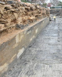 Excavation of canal at 901 N Pitt showing the wooden floor and two layers of canal stones: a rough layer covered by smoother cut stone.