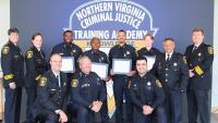 Sheriff with four recruits and several commanders and training staff members, all in blue uniforms with ties and smiling