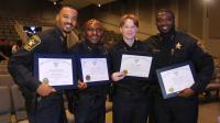 Four deputies wearing blue uniforms, holding graduation certicates and smiling