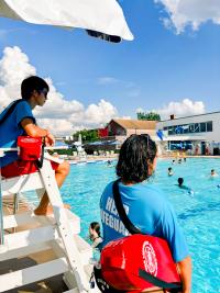 Image of two lifeguards watching an outdoor pool full of teens