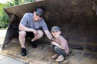 A father and son smiling inside of an excavator bucket