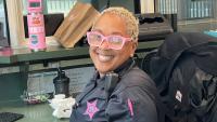 Deputy in a blue uniform with a pink embroidered badge smiling and sitting at her work station