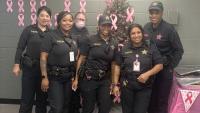 Six deputies, all wearing blue uniforms, with pink ribbons and decorations visible for a brunch for Breast Cancer Awareness Month