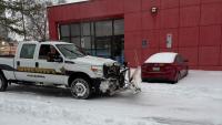 White truck with Sheriff markings and plow blade in snowy parking lot