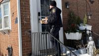 Sheriff in winter uniform delivery meals to a home with snow on the ground