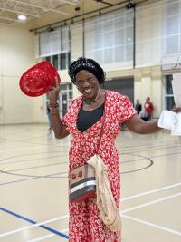 Community member wearing a red dress while holding a red plastic firefighter hat