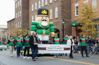 parade float with green nutcracker surrounded by eight parade volunteers