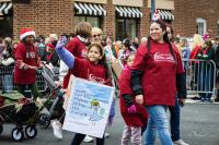 group of six people walking in the parade with red shirts on and a banner